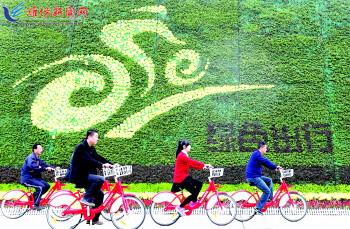 市民騎公共自行車路過市人民廣場(chǎng)一處花壇。記者 張馳